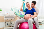 pregnant woman on a exercise ball in hospital room with husband.