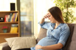 pregnant woman worried on the sofa