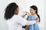 doctor performing mammogram on smiling woman patient