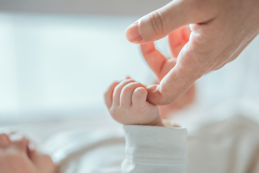 woman holding babys hand.